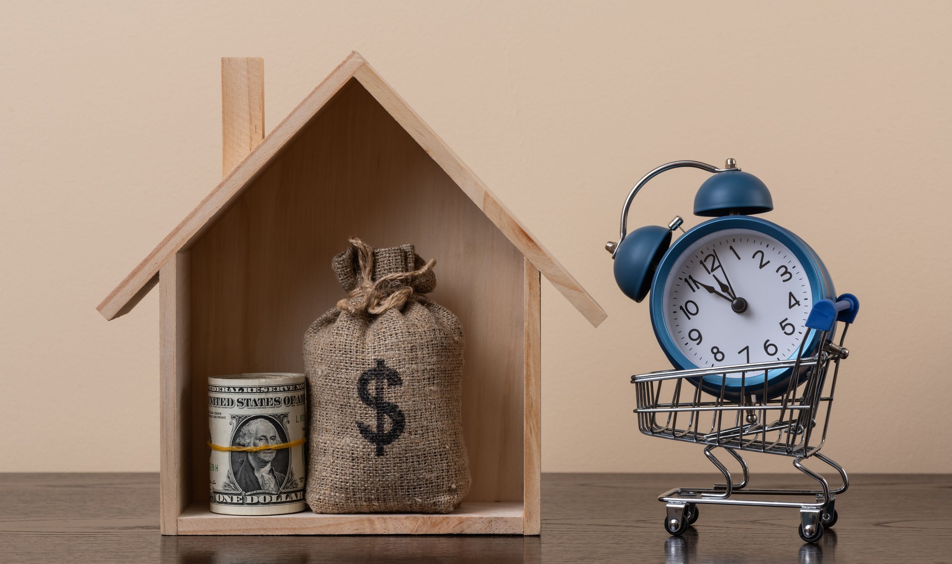 A symbolic wooden house, a stack of US$1 bills and a money bag with a dollar symbol